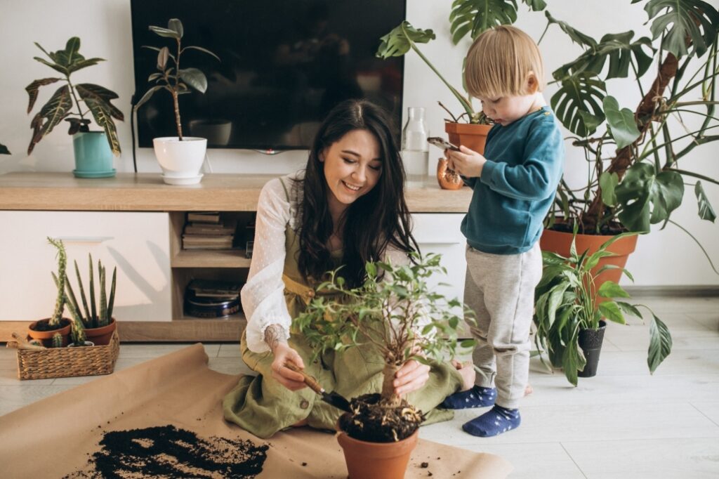 mother with little son cultivating plants at home